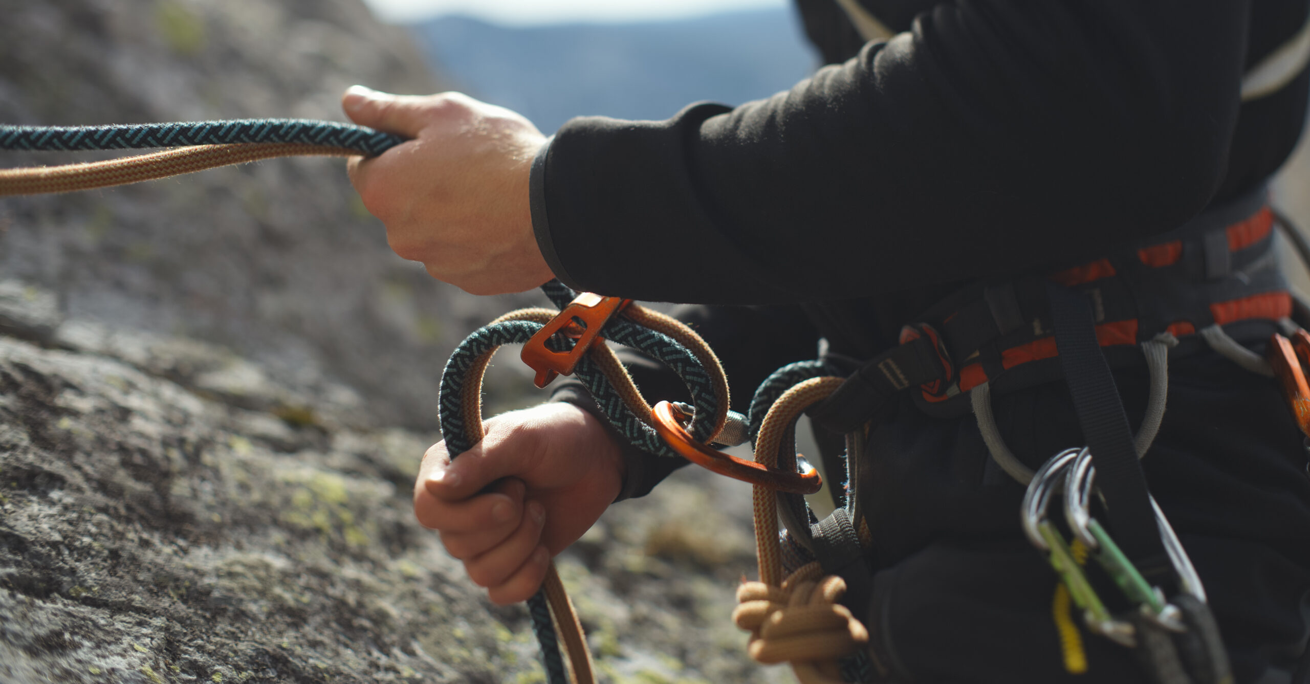 A person holding climbing ropes, and with several carabiners available to them
